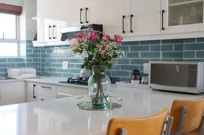 a vase of flowers sitting on a counter in a kitchen at 2 Bedroom Oceanfront Apartment with Sea Views in Cape Town