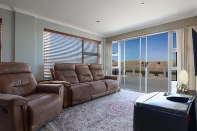 a living room with a couch and a chair at 2 Bedroom Oceanfront Apartment with Sea Views in Cape Town