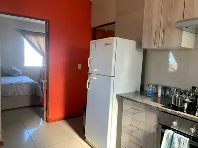 a kitchen with a white refrigerator and a red wall at manu'z in Cape Town