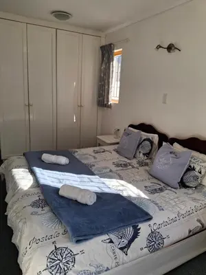 a bedroom with a bed with towels on it at Beach House on 9th in Hermanus