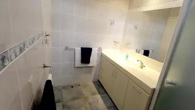 a white bathroom with a sink and a mirror at Beach House on 9th in Hermanus