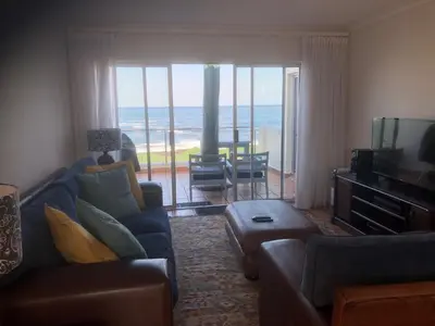 a living room with a couch and a television and the ocean at Whale Rock Estate Hermanus sea view apartment in Hermanus