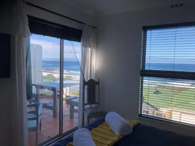a bedroom with a bed and a view of the ocean at Whale Rock Estate Hermanus sea view apartment in Hermanus