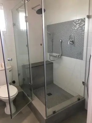 a bathroom with a glass shower with a toilet at Whale Rock Estate Hermanus sea view apartment in Hermanus
