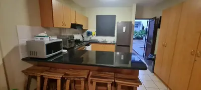 a kitchen with a counter with stools and a microwave at SEASCAPE MEWS 27 in Cape Town
