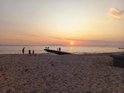 a group of people standing on a beach at sunset at Cozy Strand Beach Getaway - Studio Apartment in Cape Town