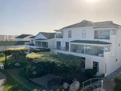 a large white house with trees and bushes at 31 Tobago Bay in Hermanus