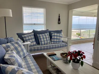 a living room with a couch and a table with a view of the ocean at 31 Tobago Bay in Hermanus