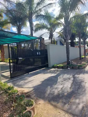 a black gate with palm trees in a yard at Mestil Guesthouse in Cape Town