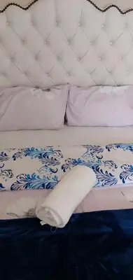a bed with a white and blue blanket and pillows at Mestil Guesthouse in Cape Town