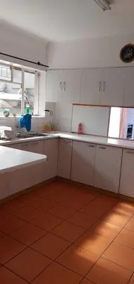 a kitchen with white cabinets and a red tile floor at Mestil Guesthouse in Cape Town