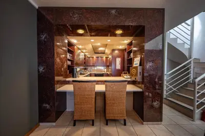 a kitchen with a bar with chairs and a staircase at Beach2Anchor, Beachfront 4 bedroom condo with Jacuzzi in Gordonʼs Bay