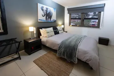 a bedroom with a bed and a picture of an elephant at Beach2Anchor, Beachfront 4 bedroom condo with Jacuzzi in Gordonʼs Bay