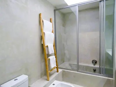 a bathroom with a shower and a toilet and a sink at Beach2Anchor, Beachfront 4 bedroom condo with Jacuzzi in Gordonʼs Bay