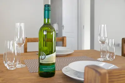 a bottle of wine sitting on top of a wooden table at Stunning, Luxurious Apartment close to the beach in Cape Town