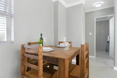 a dining room table with a bottle of wine on it at Stunning, Luxurious Apartment close to the beach in Cape Town