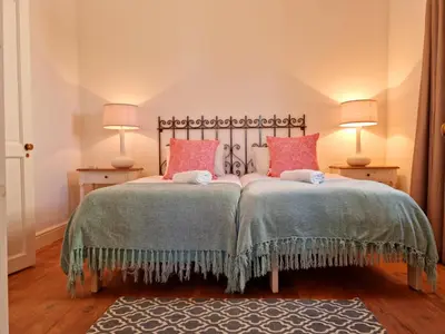 a bedroom with two beds with pink pillows at Milkwood Cottage, Beachfront family vacation home, Sleeps 6 in Gordonʼs Bay