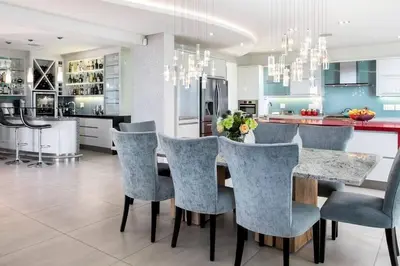 a kitchen with a dining table with blue chairs at Stamford on Sea by Top Destinations Rentals in Hermanus