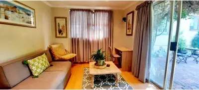 a living room with a couch and a table at Home On Uitvlugt - Peaceful leafy garden flat with sunny lounge in Cape Town