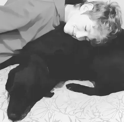 a woman laying on a bed with a black dog at Home On Uitvlugt - Peaceful leafy garden flat with sunny lounge in Cape Town