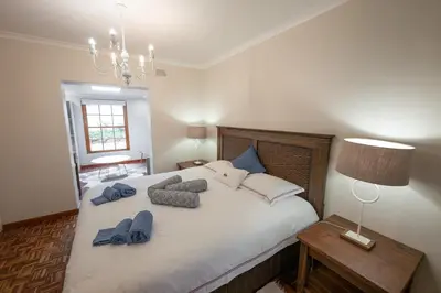 a bedroom with a large white bed with blue pillows at Saxenburg Wine Farm in Kuilsrivier