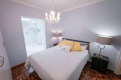 a bedroom with a white bed and a chandelier at Saxenburg Wine Farm in Kuilsrivier