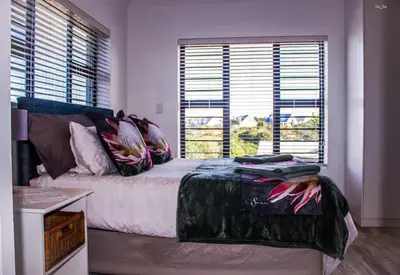 a bedroom with a bed and two large windows at 41 on Siffie in Hermanus