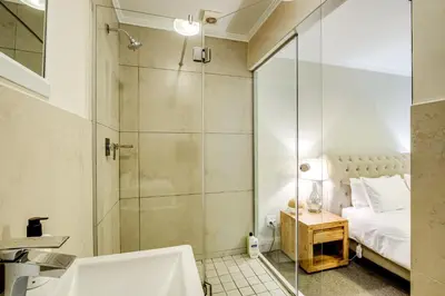 a bathroom with a shower and a bed and a sink at Quayside Canal Eden Home in Cape Town