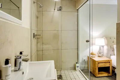 a bathroom with a shower with a glass door at Quayside Canal Eden Home in Cape Town