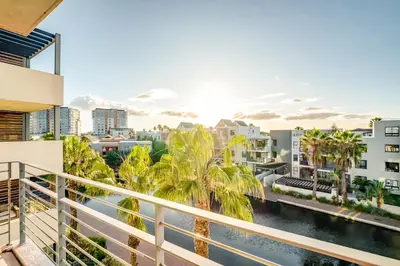 a balcony with palm trees and a view of the city at Quayside Canal Eden Home in Cape Town