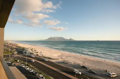 a view of a beach and the ocean with cars parked at Luxury Witsand 706 in Cape Town