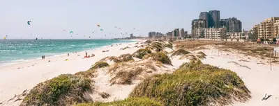 a beach with people flying kites over the ocean at Luxury Witsand 706 in Cape Town
