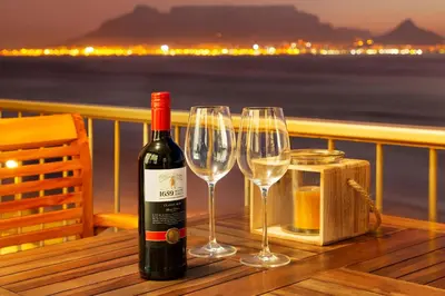 a bottle of wine sitting on a table with two wine glasses at Luxury Witsand 706 in Cape Town