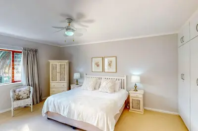 a bedroom with a white bed and a ceiling fan at The Links by Top Destinations Rentals in Hermanus