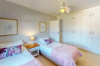 a bedroom with two beds and a ceiling fan at The Links by Top Destinations Rentals in Hermanus