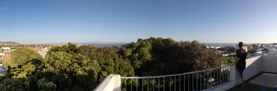 a balcony with a view of trees and the ocean at Seaclusion in Hermanus