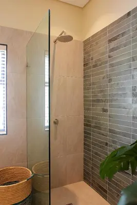 a bathroom with a shower with a glass door at Jardin de la Ferme in Franschhoek