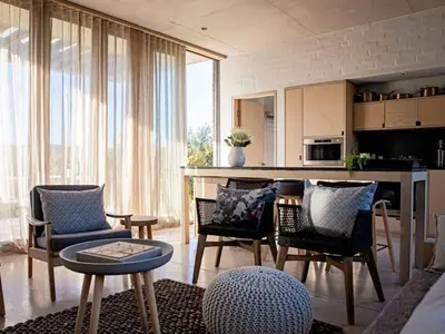 a living room with chairs and a table and a kitchen at Stonehaven Eco Cabins in Hermanus