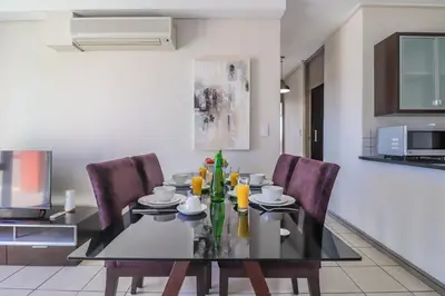 a dining room with a black table and chairs at Manhattan Towers 506 by CTHA in Cape Town