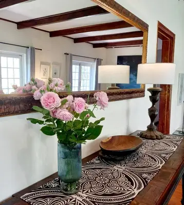a vase with pink roses on a table in a room at Porcupine Hills Olive and Guest Farm in Botrivier