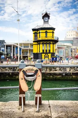 a yellow building with a clock tower in the water at Prestigious Guest Villa in Cape Town