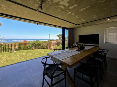 a dining room with a table and chairs and a large window at iMoyo Ocean Villa and Studio, Hermanus in Hermanus