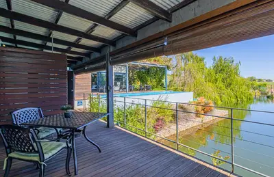 a deck with a table and chairs and a view of the water at Ladybird Boutique Hotel at Kanonkop in Stellenbosch