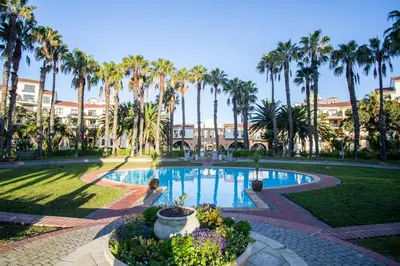 a swimming pool in a park with palm trees at Century City Luxury 2 bedroom apartment in Cape Town in Cape Town