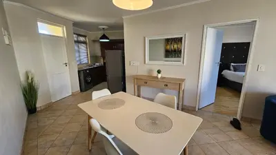 a kitchen and dining room with a table and chairs at La Palmera - Island Club Canal Front in Cape Town