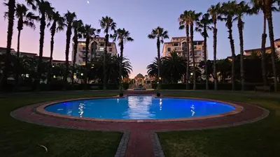 a large pool in a park with palm trees at La Palmera - Island Club Canal Front in Cape Town