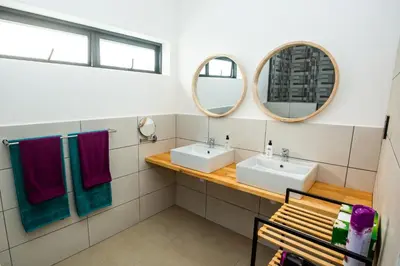 a bathroom with two sinks and two mirrors at Casa iLanga guesthouse in Somerset West