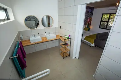 a bathroom with two sinks and two mirrors at Casa iLanga guesthouse in Somerset West