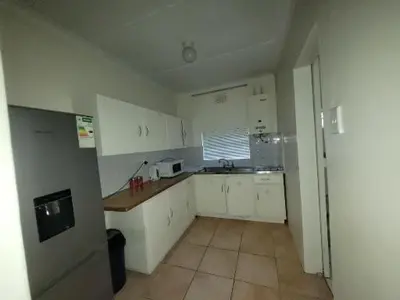 a small kitchen with white cabinets and a window at Zenith House Boston Self Catering Accomodation in Cape Town