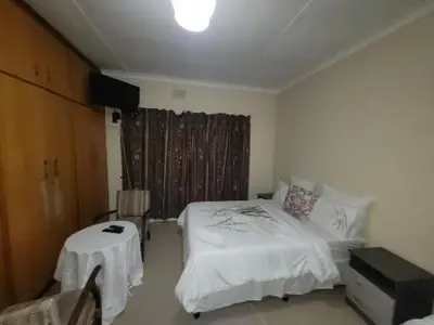 a bedroom with a bed and a table in it at Zenith House Boston Self Catering Accomodation in Cape Town